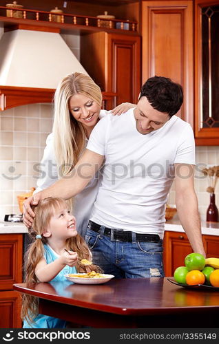 Parents look at the child which eats corn-flakes on kitchen