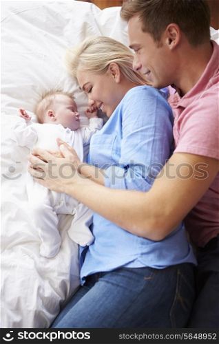 Parents Lying With Baby Girl In Bed Together