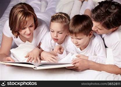 Parents of children reading a book in bed
