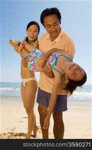 Parents Playfully Carrying Daughter on Beach