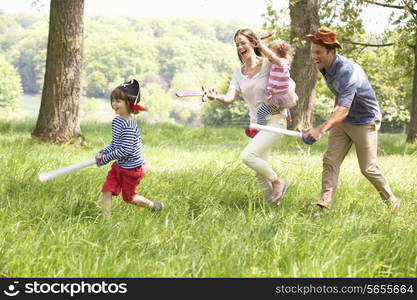 Parents Playing Exciting Adventure Game With Children In Summer Field