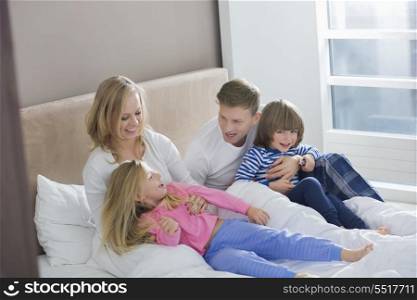 Parents playing with children in bedroom