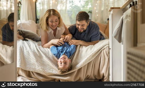 parents playing with their son caravan s bed