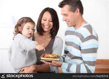 Parents preparing a bite to eat for little girl