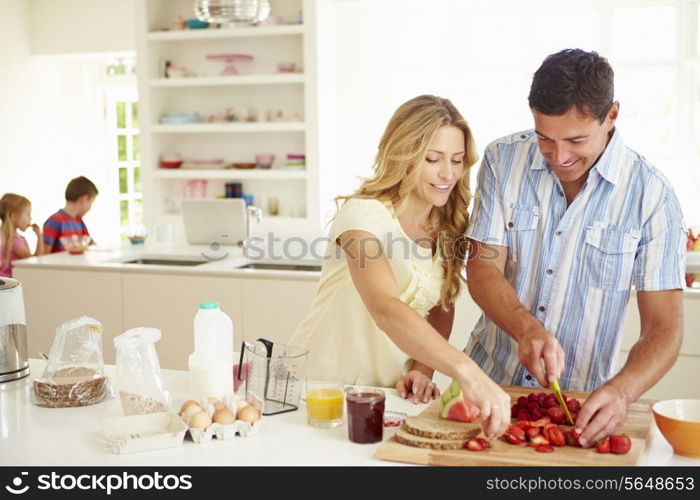 Parents Preparing Family Breakfast In Kitchen