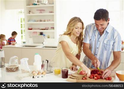 Parents Preparing Family Breakfast In Kitchen
