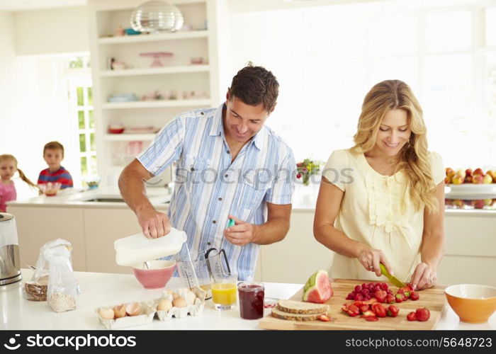 Parents Preparing Family Breakfast In Kitchen