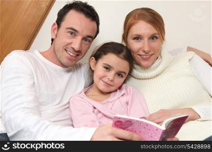 Parents reading a bedtime story to their daughter