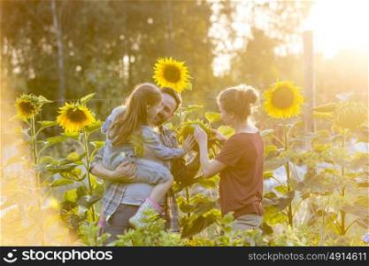 Parents showing sunflower to daughter at farm