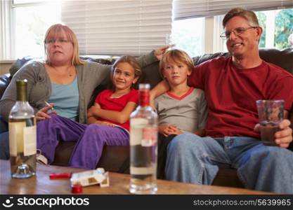 Parents Sit On Sofa With Children Smoking And Drinking