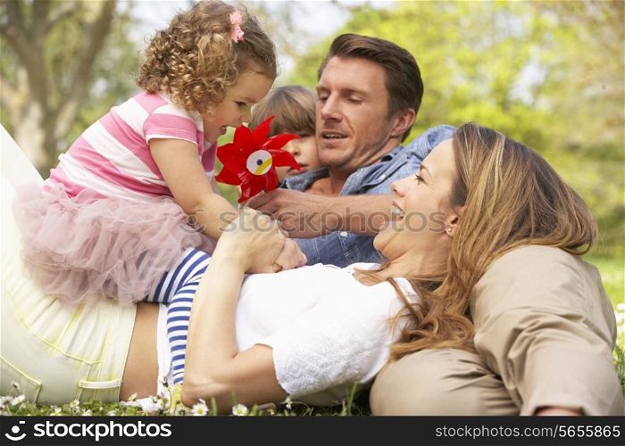 Parents Sitting With Children In Field Of Summer Flowers