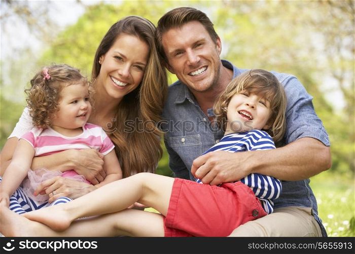 Parents Sitting With Children In Field Of Summer Flowers