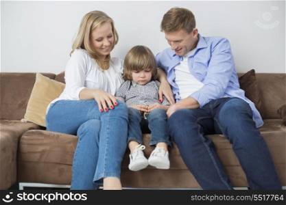Parents sitting with sad son on sofa at home