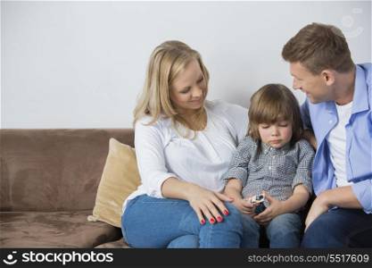 Parents sitting with upset son on sofa at home