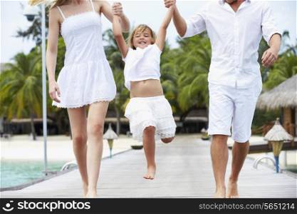 Parents Swinging Daughter As They Walk Along Wooden Jetty