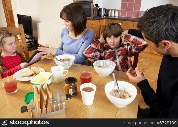 Parents Taking Away Gadgets From Children Whilst Eating Breakfast Together In Kitchen