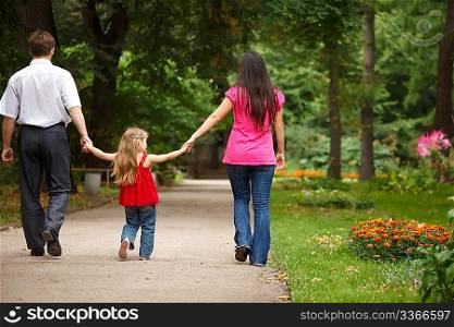 Parents together with daughter walk on summer garden. Leave afar keeping for hands.