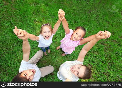 Parents with children stand having joined hands and having lifted them, top view, wide angle