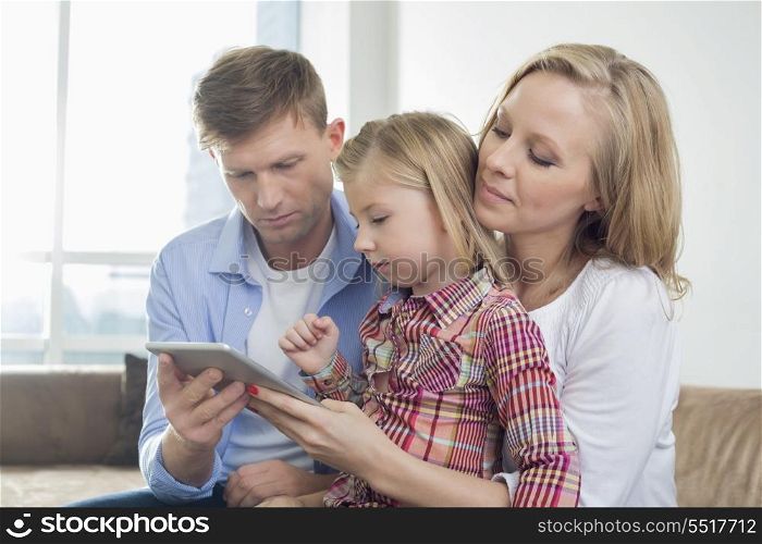 Parents with daughter using digital tablet at home