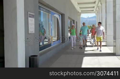 Parents with son and grandparents walking through the automatic doors of supermarket. Family going shopping together