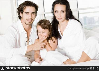 Parents with their daughter on the bed