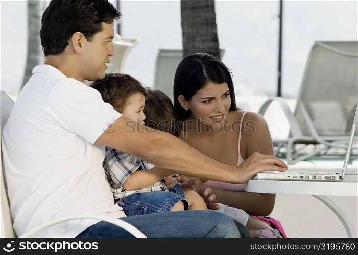Parents with their two children sitting in front of a laptop