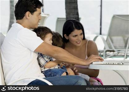 Parents with their two children sitting in front of a laptop