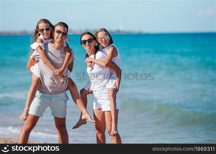 Parents with two kids have fun on the beach. Young family on vacation have a lot of fun