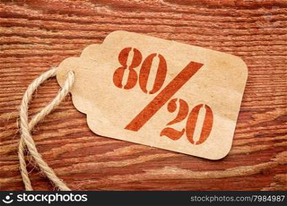Pareto principle or eighty-twenty rule represented on a paper price tag against rustic wood
