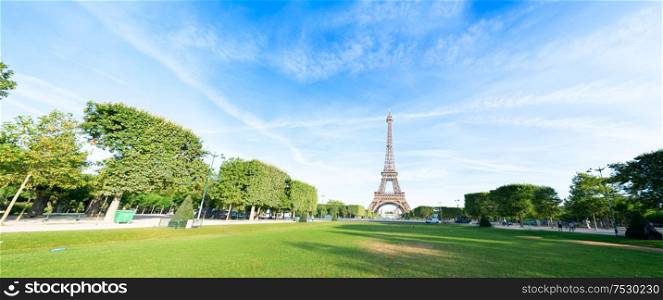 Paris Eiffel Tower over green grass lane in Paris, France. Web banner format. Eiffel Tower is one of the most iconic landmarks of Paris.. eiffel tour and Paris cityscape
