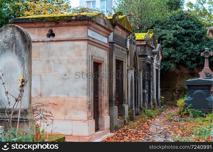 Paris, France - November 14, 2019: A view on autumn alley of the most famous cemetery of Paris Pere Lachaise, France. Tombs of various famous people. Golden autumn over eldest tombs.