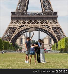 PARIS - JULY 27: Newly wed couple at the Eiffel Tower on July 27, 2013, in Paris. The Eiffel Tower is the most visited tourist attraction in France and one of the most recognizable landmarks in the world.