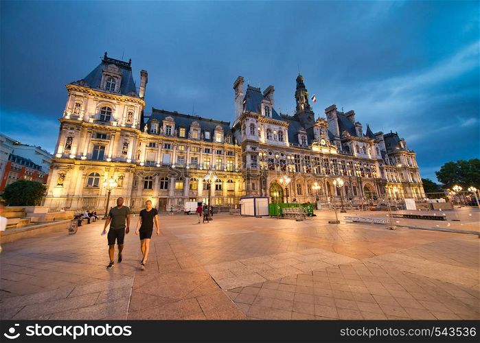 PARIS - JUNE 2014: Hotel de Ville at night with tourists. Paris attracts 30 million people annually.