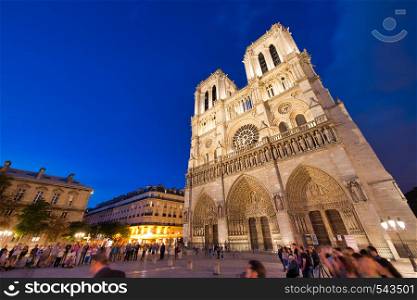 PARIS - JUNE 2014: Notre Dame Cathedral at night with tourists. Notre Dame is visited by 12 million people every year.
