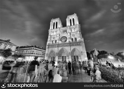 PARIS - JUNE 2014: Notre Dame Cathedral at night with tourists. Notre Dame is visited by 12 million people every year.