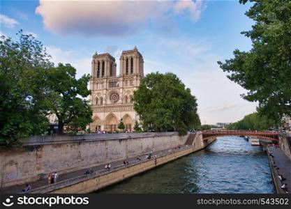 PARIS - JUNE 2014: Notre Dame Cathedral at sunset with tourists. Notre Dame is visited by 12 million people every year.