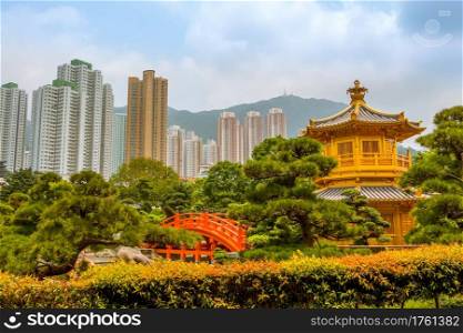 Park in Hong Kong. Golden Pavilion surrounded by plants and trees. Skyscrapers and mountains in the background. Golden Pavilion and Skyscrapers of Hong Kong