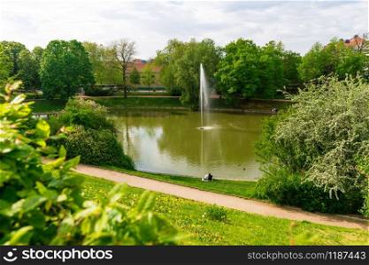 Park with a pond in old European town. Summer tourism and travels, famous europe landmark, popular places and streets