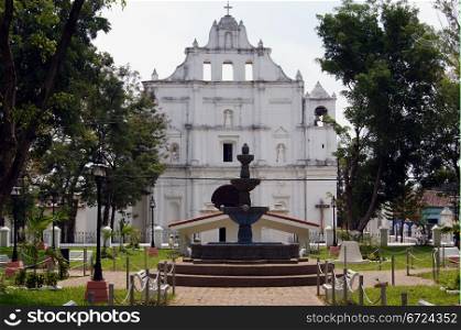 Park with fountain and white church in Chaichuapa, Salvador