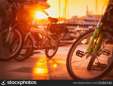 Parking for bicycles on the pier near yacht port, many different bicycles in bright sunset light, eco transport, healthy and active lifestyle, urban street scene