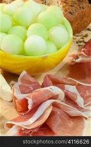Parma Ham, balled melon, bread and cheese illuminated by golden sunshine