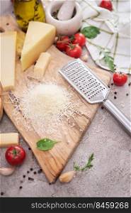 Parmesan cheese and grater on a wooden cutting board.. Parmesan cheese and grater on a wooden cutting board
