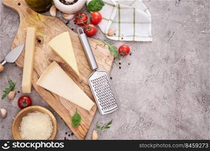 Parmesan cheese and grater on a wooden cutting board.. Parmesan cheese and grater on a wooden cutting board
