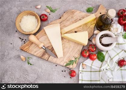 Parmesan cheese and knife on a wooden cutting board.. Parmesan cheese and knife on a wooden cutting board