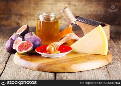 parmesan cheese with fresh figs and honey on wooden background