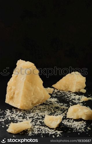 Parmigiano chunks on an old kitchen table, ripe cheese from a farm. Natural product of Mediterranean cuisine