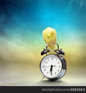 Parrot sitting on alarm clock. Image of yellow parrot sitting on alarm clock