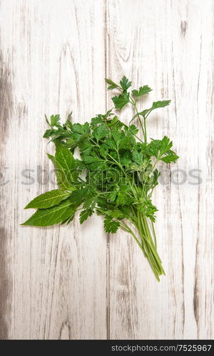 Parsley and bay laurel leaves on wooden background. Fresh organic herbs. Healthy food ingredients