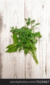 Parsley and bay laurel leaves on wooden background. Fresh organic herbs. Healthy food ingredients