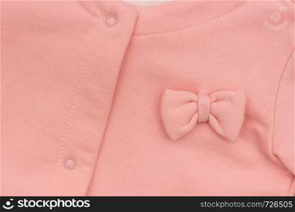 Part girl's pink elegant jacket with bow close-up, background texture.. Part girl's pink elegant jacket with bow close-up, background texture